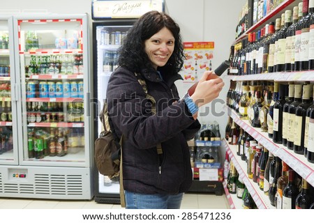MOSCOW, RUSSIA  -  APRIL 07, 2015: Woman choosing a bottle of wine in supermarket store Pyaterochka. Supermarket Pyaterochka with the most affordable prices. Russia\'s largest retailer.