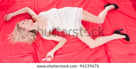 addict woman lies unconscious on the red bed sheet near a syringe