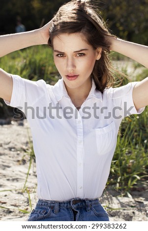 fashionable groomed young beautiful girl with long dark hair in a simple dress sits on a background of sky and shows his hands and eyes banners and inscriptions