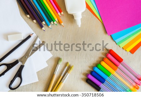 Colored paper, felt-tip pens, pencils, painting brushes, scissors, glue on wooden background