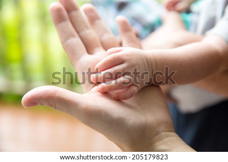 Royalty free image of a baby\'s hand on top of mother\'s hand. Shallow depth of field.