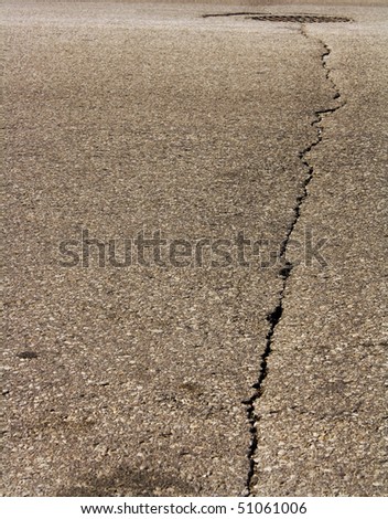 Large crack in road leading to a sewer drain