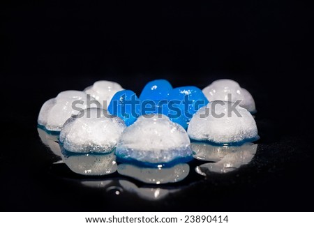 Coloured (blue and white) ice, on black background. Top  spot light. Focus accent on center of composition