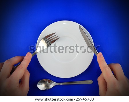 Fork, knife  in hands on  blue background.Spotlight source on top.