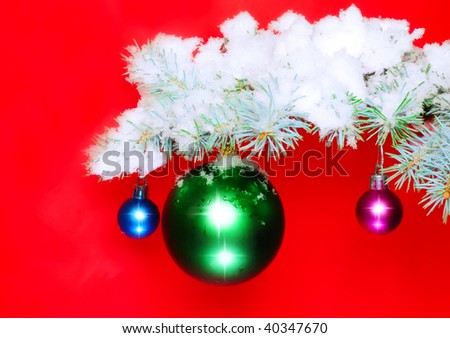 Christmas and New Year decoration- balls on snow-covered fir branches .On red  background