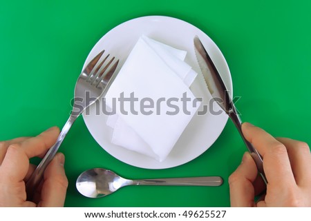 Table serving- knife,fork in hands  on green   backgroung.