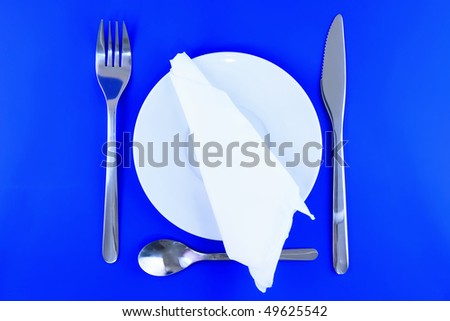 Table serving- knife, spoon, fork and silk napkin  on blue   backgroung.