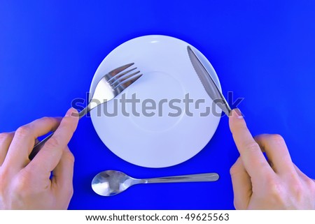 Table serving- knife,fork in hands  on blue   backgroung.