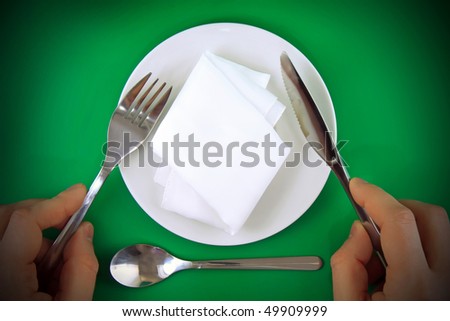 Table serving-knife, fork in hands  and silk napkin on green  background.Spotlight source on top and in center.