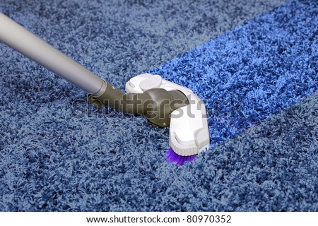 The metal pipe of vacuum cleaner in action - clean stripe on the carpet.