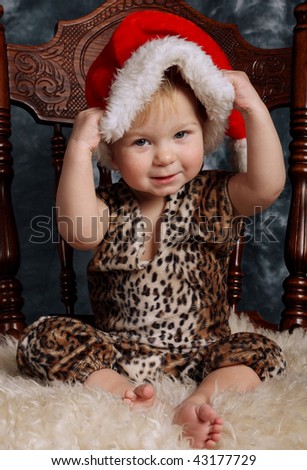 Little boy sitting on a fur dresses up santa\'s hat