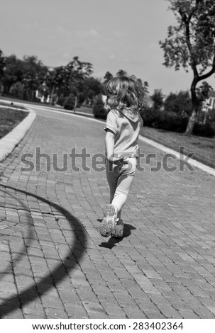 A little girl running along the path of a park, black and white photo
