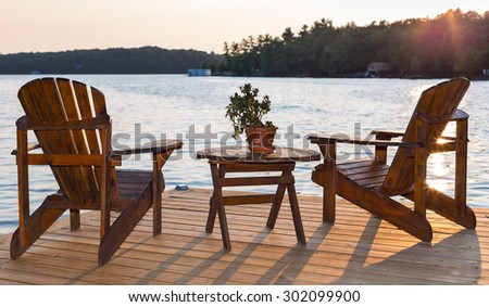 Chairs on a deck overlooking a lake at sunset