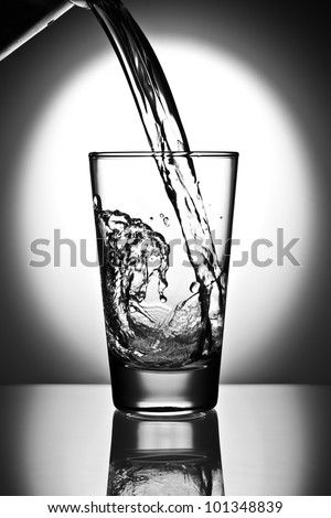 water pouring into a glass on a reflective surface