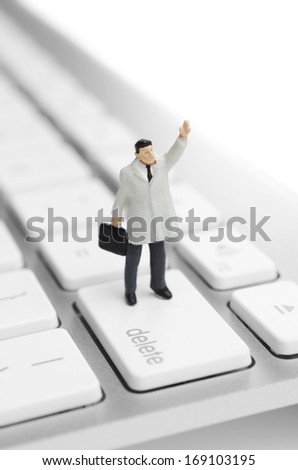 Looking for a job online. Business figure placed on the delete key on a computer keyboard.