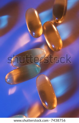 Vitamin E gel tablets illuminated with blue and orange lighting