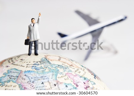 Business figurine on earth globe with toy airplane in background