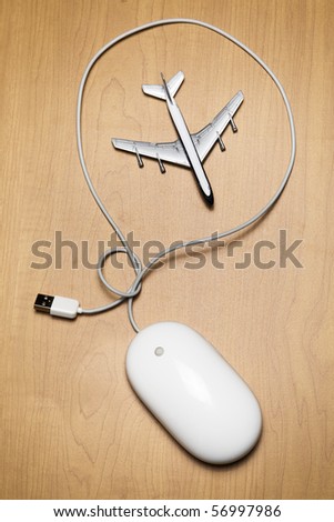 White computer mouse and a toy airplane on a wood tabletop