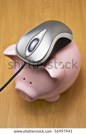 Metallic color computer mouse on top of a pink piggy bank