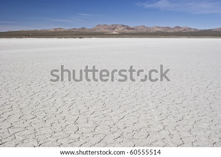 Desert revealing cracked earth, mountains and blue sky
