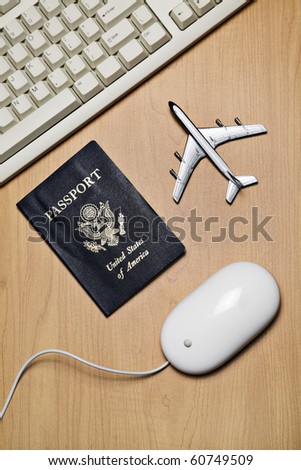 White computer mouse, toy airplane and passport on a wood tabletop
