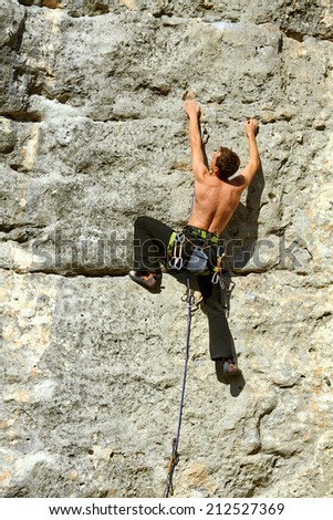 Young man climbs on a rocky wall