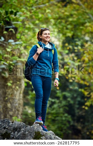Active healthy woman hiking in beautiful forest. Portrait of happy smiling young woman resting of forest clearing during hike holidays.