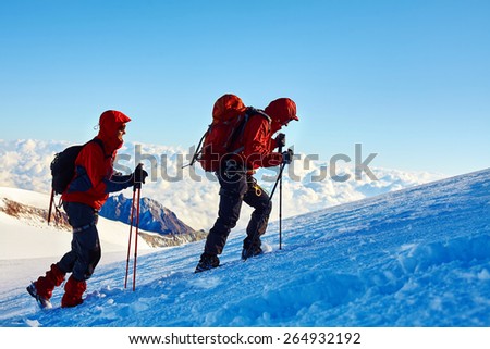 climbers at the top of a pass with backpacks meeting the sunrise in the mountains