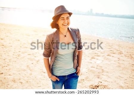 young woman on the sea beach at the morning. woman dressed in sneakers jeans jacket and hat