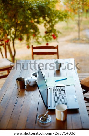 Laptop computer, phone and coffee in the garden - freelance or remote work concept. small depth of field, focus on the keyboard
