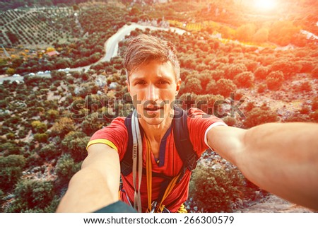 young attractive man make selfie from the cliff on the gardens background