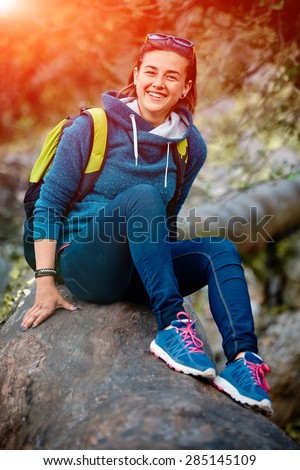 Active healthy woman hiking in beautiful forest. Portrait of happy smiling young woman resting of forest clearing during hike holidays.