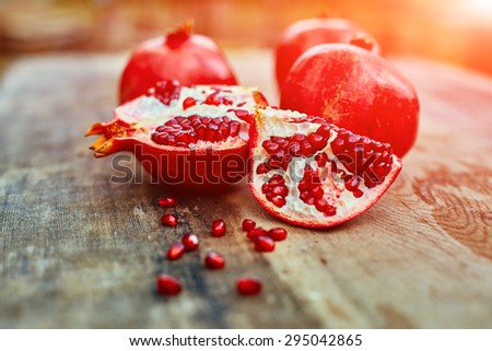 ripe cracked raw pomegranates on a dark wooden background