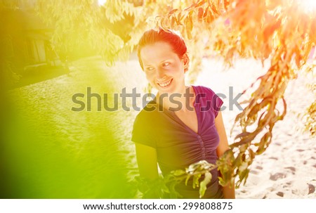 woman in shirt under olive tree on sea sand background