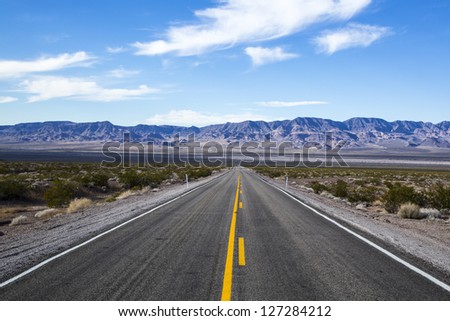 Long desert highway to the mountains under the hot sun