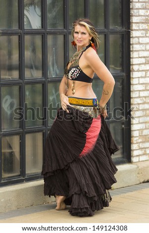 Tribal fusion belly dance costume with 25 yard skirt, fringe and kuchi belt with coin and shell bra, typically accessorized with metal earrings, choker type necklace, multiple arm bands and rings.