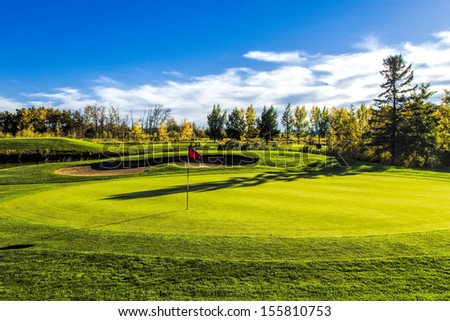 The fall colors of autumn surround the greens of the golf course