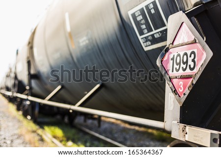 Railroad train of  black tanker cars transporting crude oil on the tracks. Hazardous material sign 1993 denoting flammable liquids.