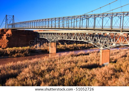 Cameron Suspension Bridge spans the Little Colorado River upstream from the Grand Canyon. In 1958, the Hwy Bridge was built alongside, and the old suspension bridge was converted to a pipeline bridge.