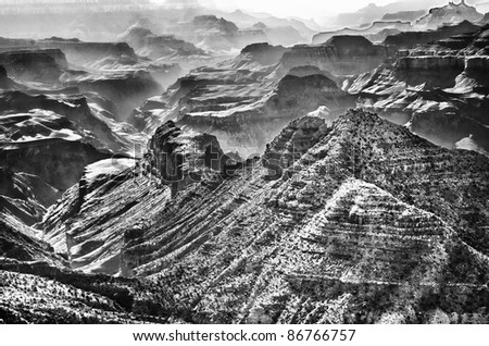 The Grand Canyon in black and white with smoke and smog between the walls of the canyon.