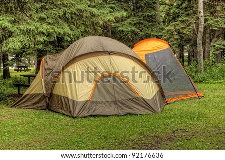 Heavily wooded camp site with a large tent set up for the night