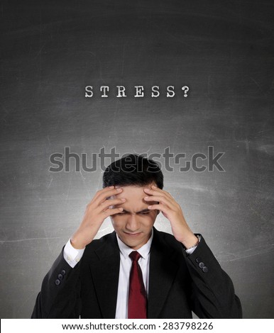Conceptual image of work stress. Young Asian businessman having depression with both hands holding his head, on dark grunge background