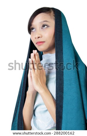 Young Asian woman in veil looking up and praying with closed hands gesture, isolated on white background