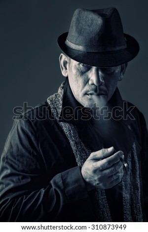 Vintage style portrait of an old private investigator smoking a cigarette in cool attitude