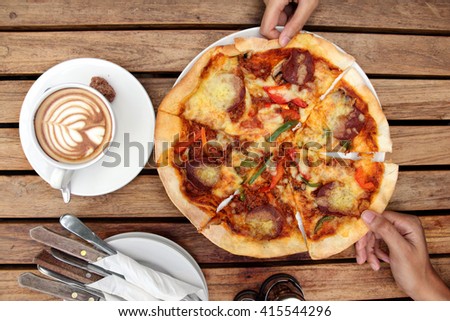 Pizza dining. Two hands taking pizza slices, on top of wooden table, overhead shot