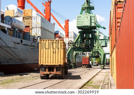 Cargo truck, loaded with container, is driving to a unload point next to massive port crane, at container terminal at Varna port, Varna, Bulgaria, May 16, 2014.