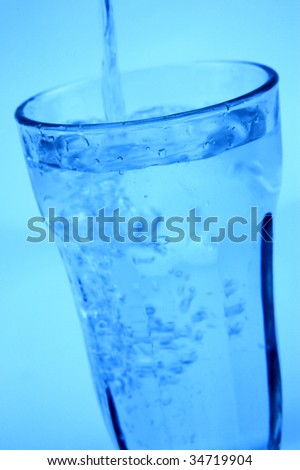 Water pouring into a glass isolated against a blue background