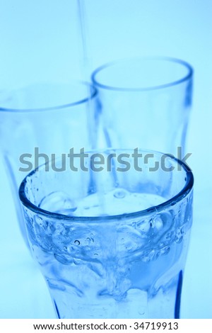 Water pouring into a glass isolated against a blue background