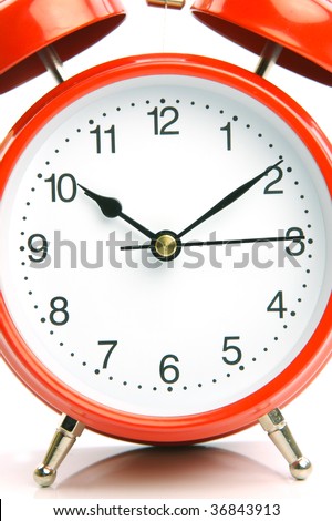 An old fashion analogue alarm clock set against a white background