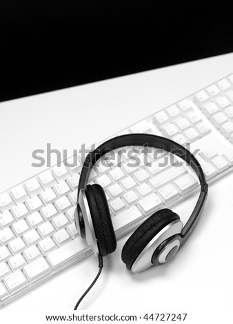 A desktop computer with a set of headphones isolated against a white background